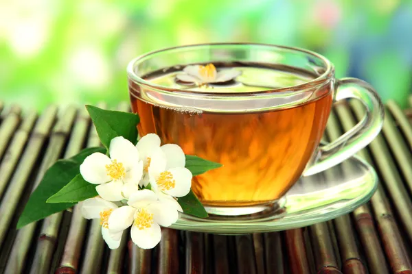Xícara de chá com jasmim, em esteira de bambu, close-up — Fotografia de Stock