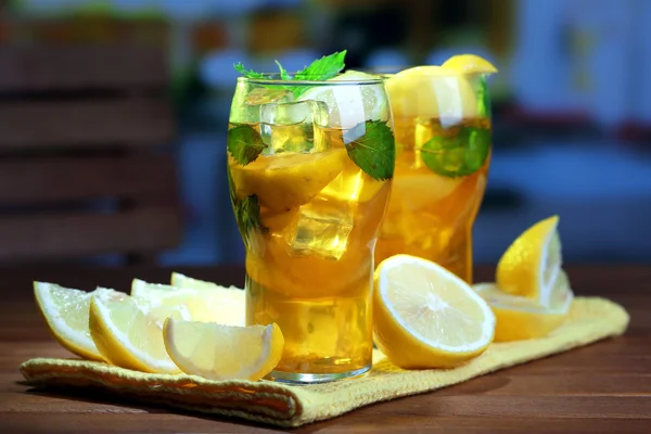 Té helado con limón y menta en la mesa de madera, al aire libre —  Fotos de Stock