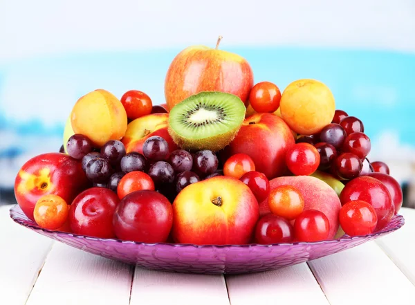 Assortment of juicy fruits on wooden table, on bright background — Stock Photo, Image