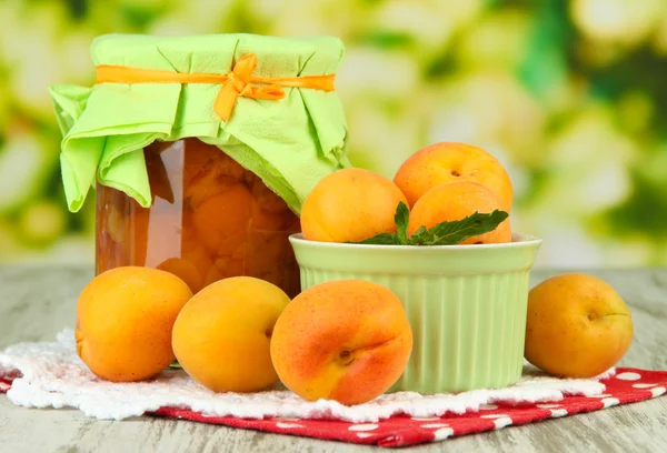 Meruňkový džem do sklenic a čerstvé meruňky, na dřevěný stůl, na světlé pozadí — Stock fotografie
