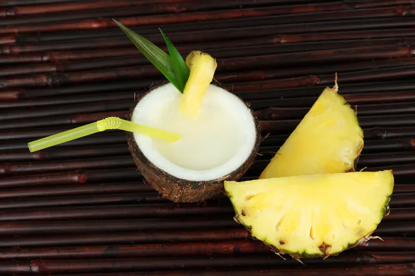 Bebida de piña colada en coco, sobre fondo de estera de bambú —  Fotos de Stock