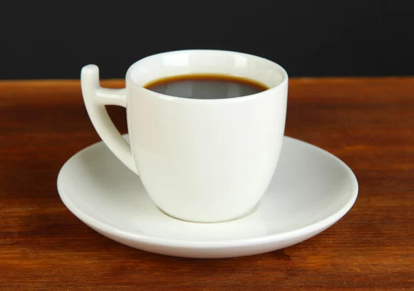 Cup of coffee on wooden table on black background — Stock Photo, Image