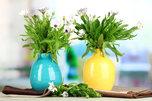 Buquê de belas flores de verão em vasos de cor, na mesa de madeira, no fundo brilhante — Fotografia de Stock