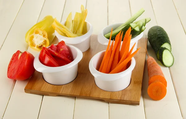 Légumes frais brillants coupés en tranches dans des bols sur une table en bois close-up — Photo