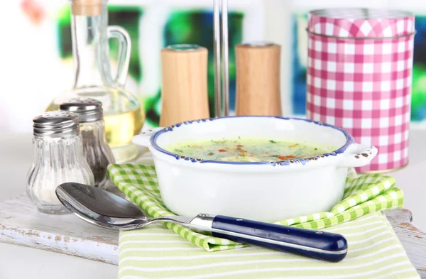 Суп в тарелке на салфетке на деревянной доске на фоне окна — стоковое фото