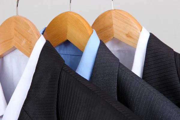 Suits with shirts on hangers on light background — Stock Photo, Image