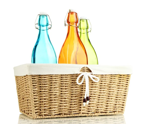 Hasır sepet, üzerinde beyaz izole renkli cam şişelerde — Stok fotoğraf