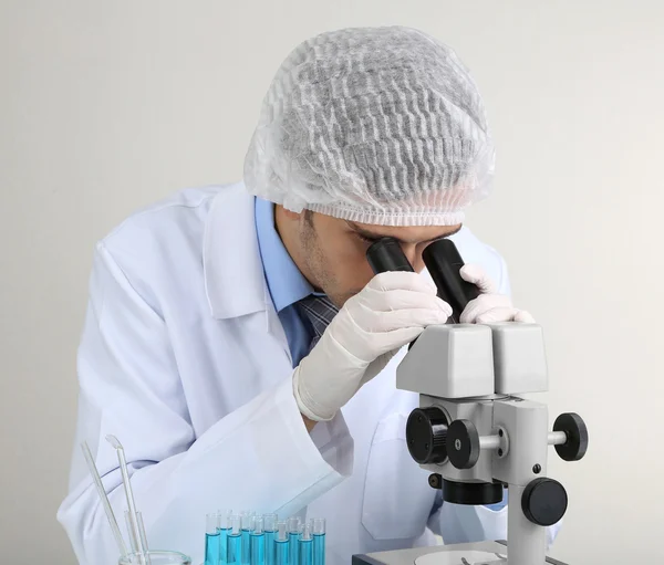 Científico de laboratorio joven mirando el microscopio en el laboratorio — Foto de Stock