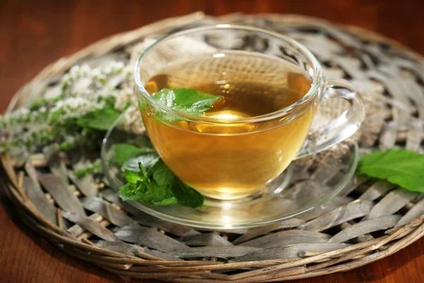 Чашка травяного чая со свежими мятными цветами на деревянном столе — стоковое фото