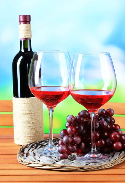 Sklenice vína na pletené zásobník na dřevěný stůl na pozadí přírody — Stock fotografie