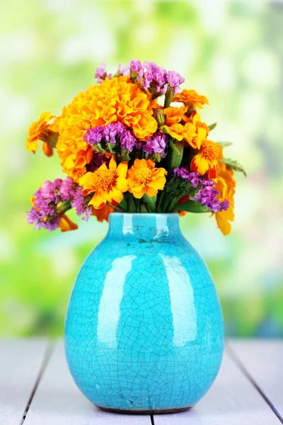 Bouquet of marigold flowers in vase on wooden table on natural background — Stock Photo, Image