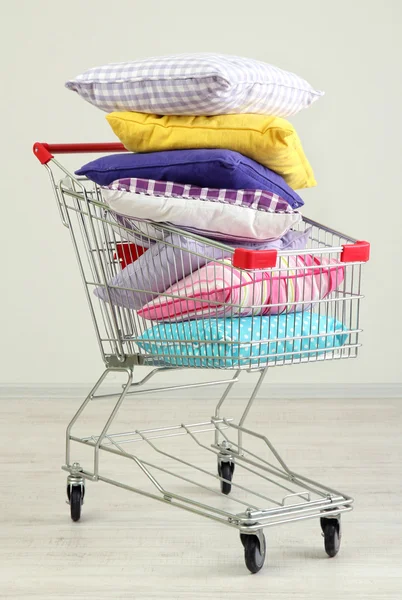 Carrinho de compras com travesseiros, em fundo cinza — Fotografia de Stock