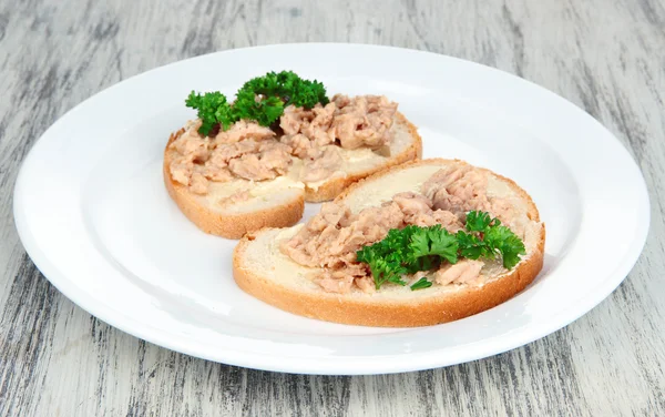 Läckra smörgåsar med tonfisk och torsk lever sardiner, på vit platta. på trä bakgrund — Stockfoto