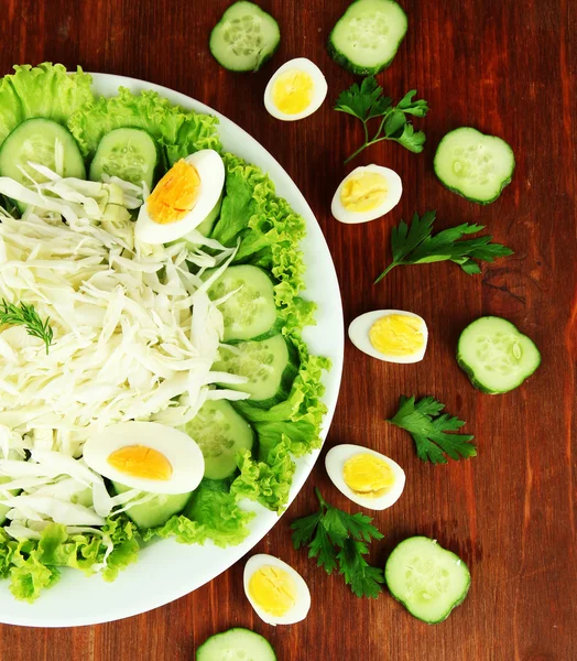 Νόστιμη σαλάτα με αυγά, λάχανο και αγγούρια στο ξύλινο τραπέζι — Φωτογραφία Αρχείου