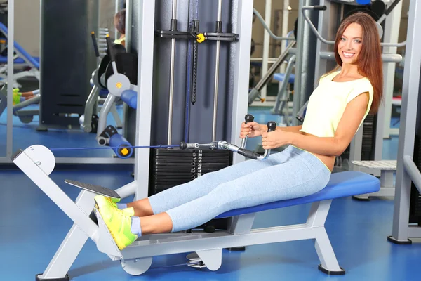 Pretty sporty girl engaged in simulator in gum — Stock Photo, Image