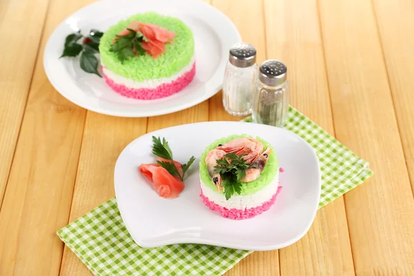 Цветной рис на тарелках на салфетке на деревянном столе — стоковое фото