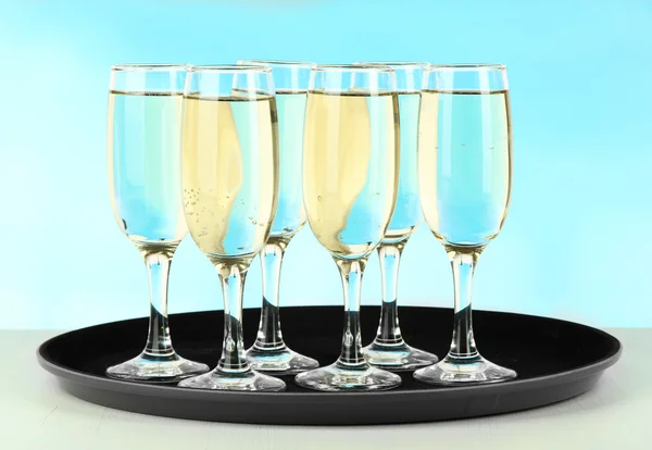 Many glasses of champagne on the tray on table, on blue background — Stock Photo, Image