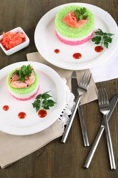 Gekleurde rijst op platen op servetten op houten tafel — Stockfoto