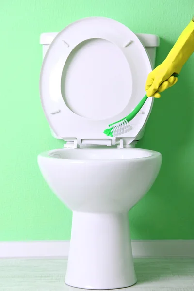 Mão de mulher com escova limpando um vaso sanitário em um banheiro — Fotografia de Stock