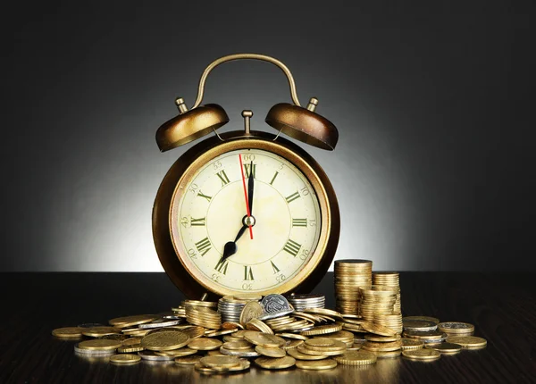 Starožitné hodiny a mince na dřevěný stůl na černém pozadí Royalty Free Stock Obrázky