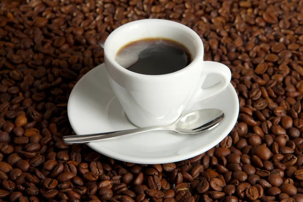 Xícara de café em grãos de café fundo — Fotografia de Stock