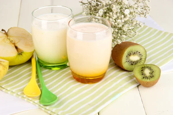 Deliciosos yogures con frutas en vasos sobre mesa de madera — Foto de Stock