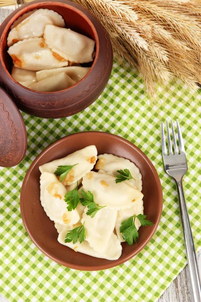 Tasty dumplings with fried onion on brown plate, on wooden background — Stock Photo, Image