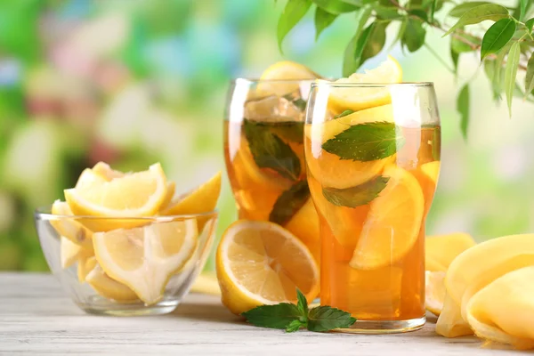 Té helado con limón y menta en la mesa de madera, al aire libre —  Fotos de Stock