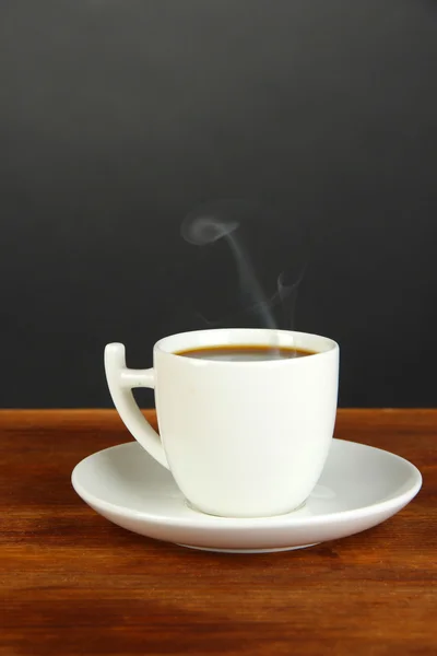 Taza de café sobre mesa de madera sobre fondo negro —  Fotos de Stock