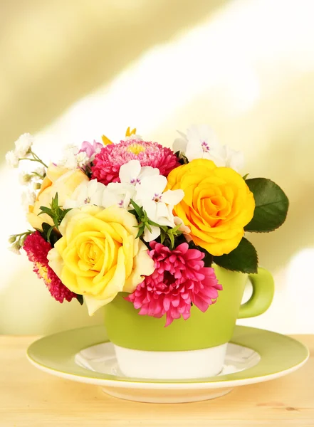 Красивый букет ярких цветов в цветной кружке, на деревянном столе, на ярком фоне — стоковое фото