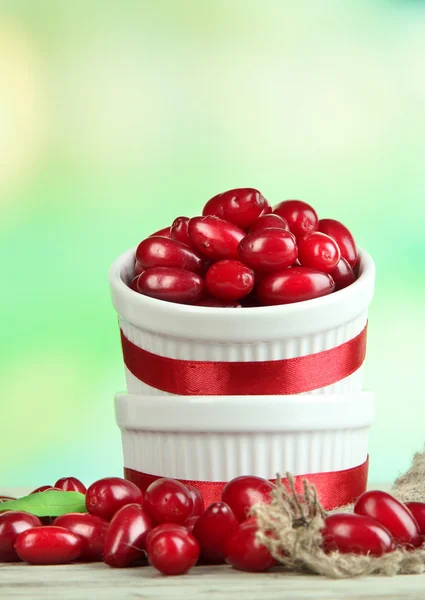 Fresh cornel berries in white cups on wooden table — Stock Photo, Image