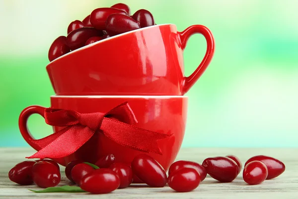 在木桌上的红色杯子新鲜山茱萸浆果 — 图库照片