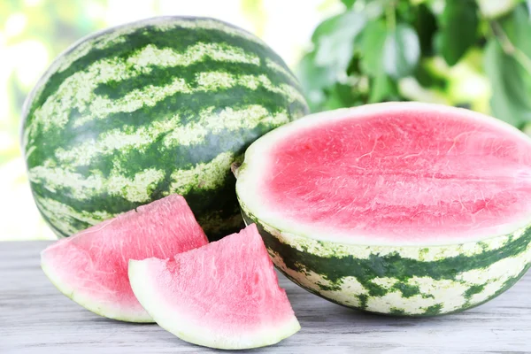 Reife Wassermelonen auf Holztisch auf Naturhintergrund — Stockfoto