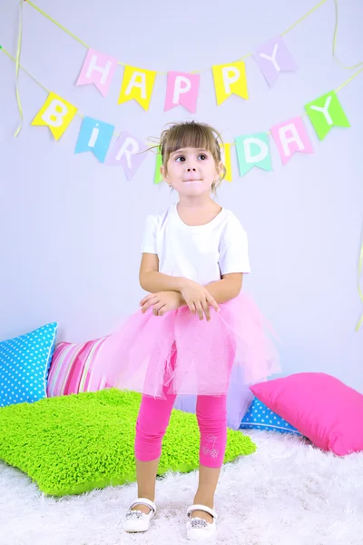 Kleines Mädchen tanzt auf Bett im Zimmer auf grauem Wandhintergrund — Stockfoto