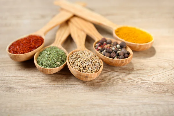 Assortment of spices in wooden spoons on wooden background — Stock Photo, Image