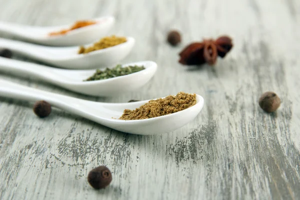 Assortment of spices in white spoons, on wooden background — Stock Photo, Image