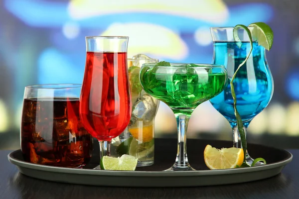 Nombreux verres de cocktails sur plateau sur table, sur fond lumineux — Photo