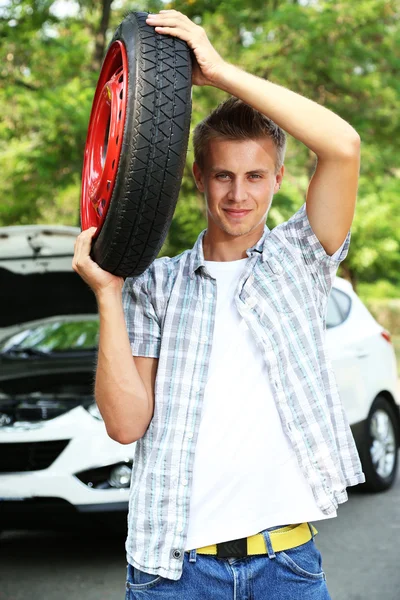 Hombre conductor sosteniendo neumático en hombro — Foto de Stock