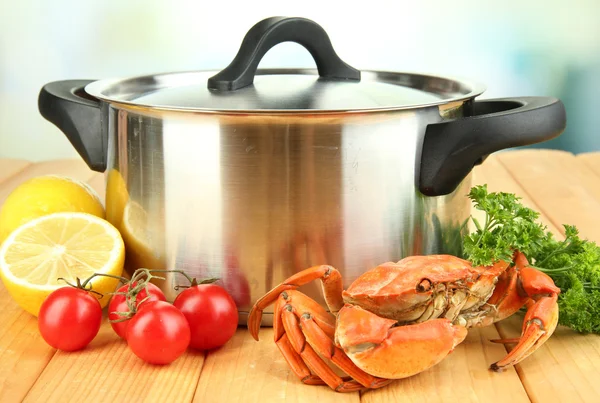 Composition with boiled crab, pan and vegetables on wooden table,on bright background — Stock Photo, Image