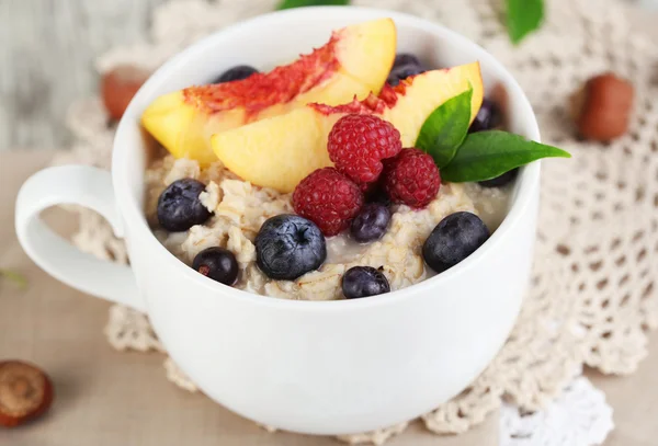 Haferflocken in Tasse mit Beeren auf Servietten auf Holztisch — Stockfoto