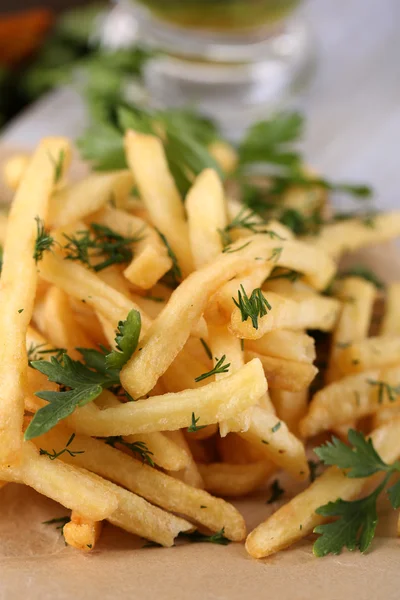 Franse frietjes op calqueerpapier aan boord op houten tafel — Stockfoto