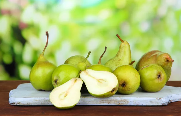 Pears on wooden cutting board, on bright background — Stock Photo, Image