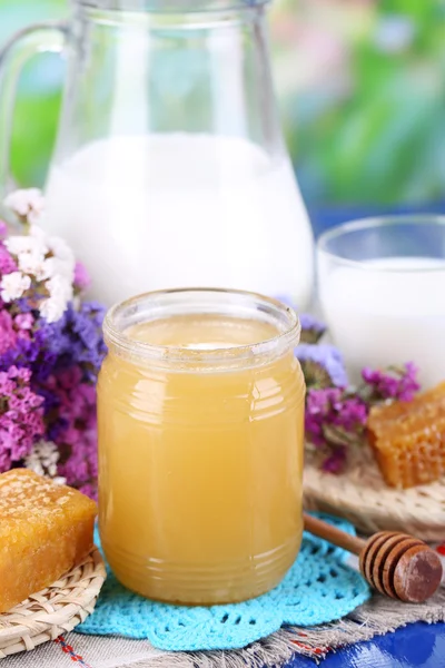 Miel et lait sur table en bois sur fond naturel — Photo