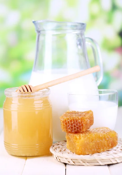 Miel et lait sur table en bois sur fond naturel — Photo