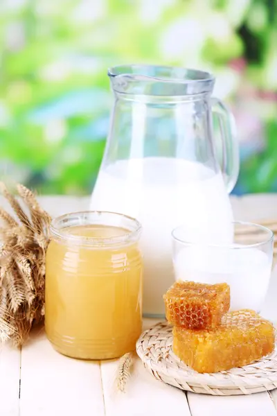 Miel y leche sobre mesa de madera sobre fondo natural — Foto de Stock