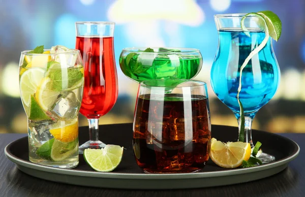 Nombreux verres de cocktails sur plateau sur table, sur fond lumineux — Photo