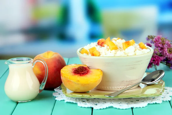 Кислый сыр и кусочки свежего персика, на деревянном столе, на ярком фоне — стоковое фото