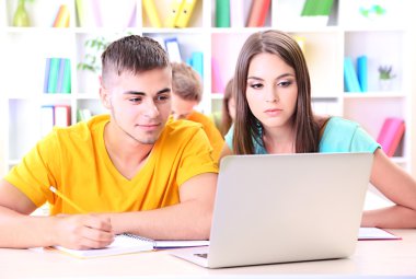 Kütüphanede oturan genç öğrenci grubu