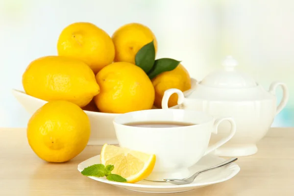 Tasse Tee mit Zitrone auf dem Tisch auf hellem Hintergrund — Stockfoto