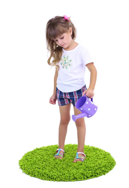 Маленькая девочка поливает зеленую траву, изолированную на белом — стоковое фото